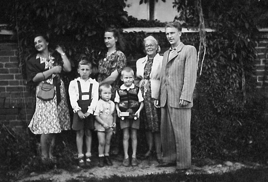 Su šeima prie mokyklos. Iš kairės: teta, pusbrolis Romas, brolis, mama,  Virgis su mašinike, senelė, tėvas. Apie 1953 m. 