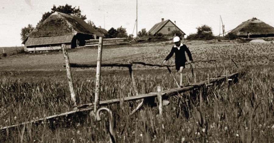 Lieptu per Šiaušės upelį eina Vytenis. Fone – Bagdoniškės pradinė mokykla. 1939 m. Pelikso Bugailiškio nuotr.